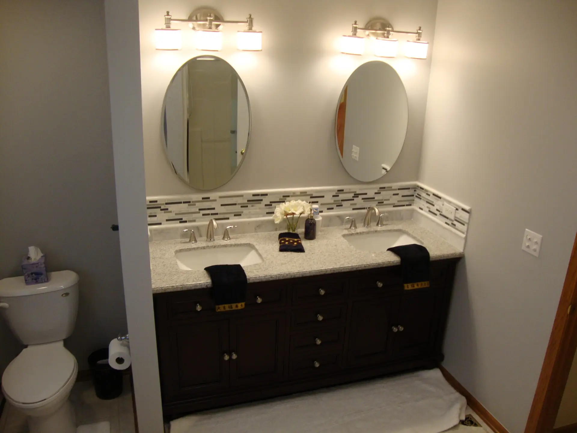 Bathroom remodel, dark double vanity, light floors and counter top with tie backsplash